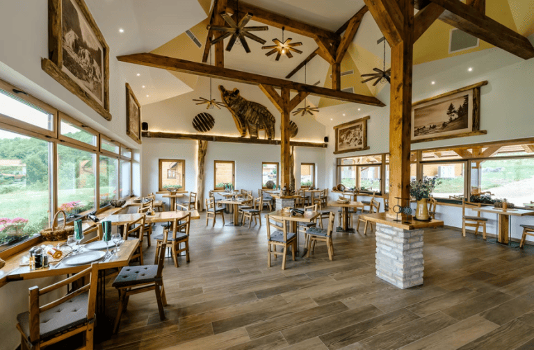 Spacious interior of La Ursula restaurant in Vrelo Koreničko featuring rustic wooden beams, a bear sculpture, and panoramic views
